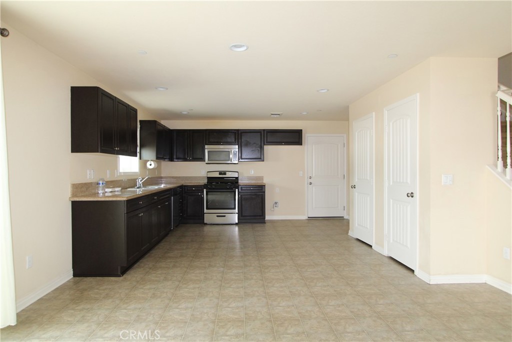 794 Brownie Way Beaumont, CA 92223 - Photo 3 of 18 a large white kitchen with stainless steel appliances a sink a stove a microwave and cabinets