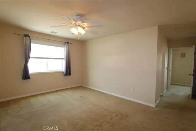 an empty room with windows and chandelier fan