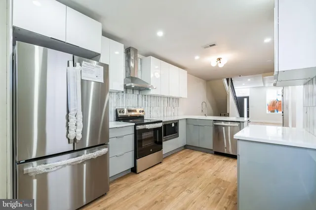 a kitchen with stainless steel appliances granite countertop a refrigerator a stove and a sink