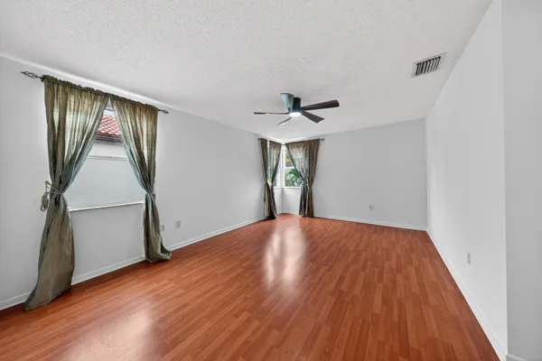 an empty room with ceiling fan and windows