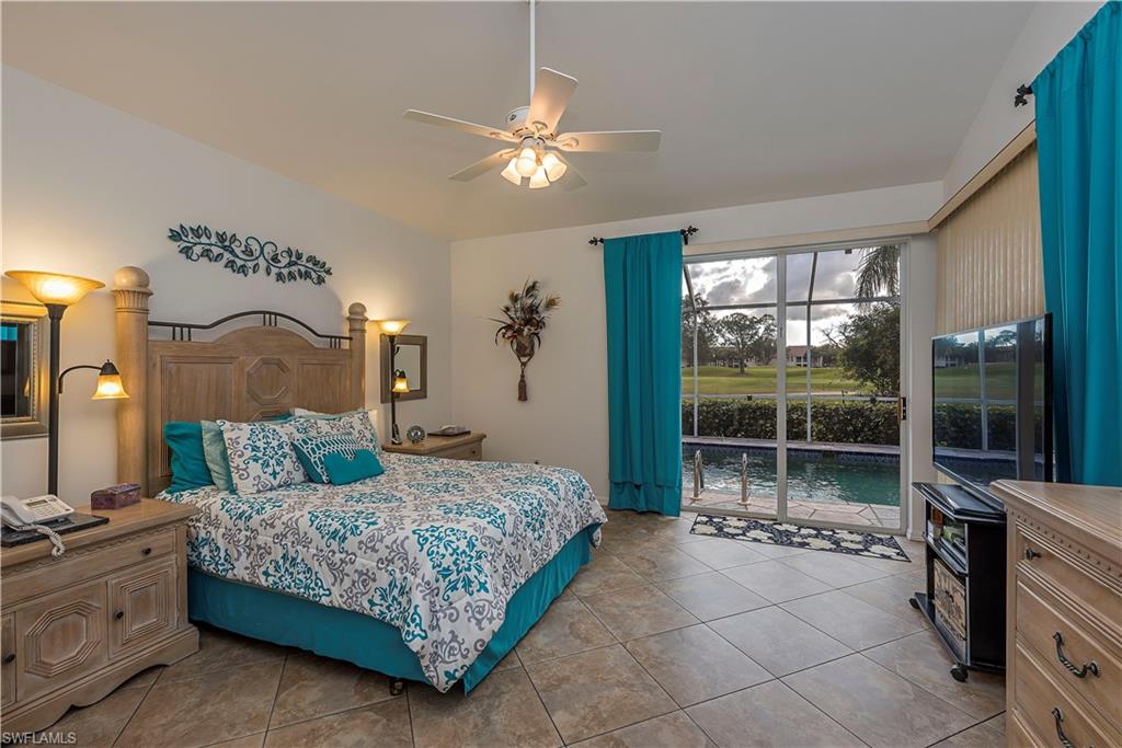 144 Napa Ridge Way Naples, FL 34119 - Photo 7 of 12 a bedroom with a large bed and a chandelier