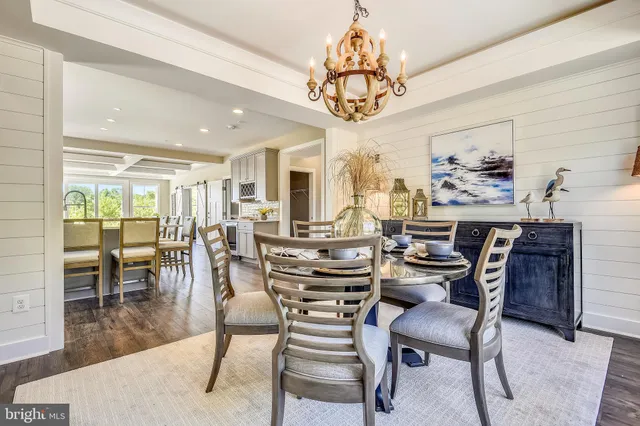 a kitchen with stainless steel appliances a table chairs refrigerator and wooden floor