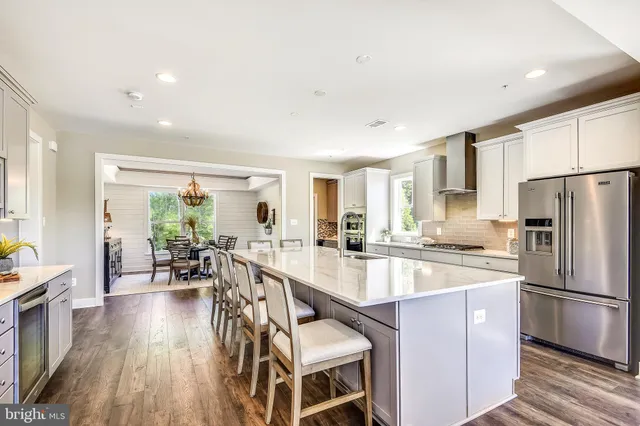 a kitchen with stainless steel appliances kitchen island granite countertop a table chairs and a refrigerator