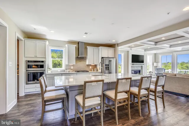 a kitchen with stainless steel appliances kitchen island granite countertop a table chairs and a refrigerator