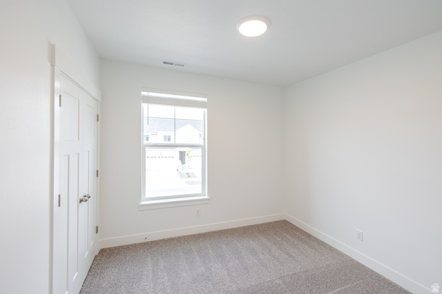 675 West 4500th South, Unit P201 Mapleton, UT 84664 - Photo 7 of 16 Carpeted interior room featuring a single window with blinds, white trim throughout, a flush-mount ceiling light, and a paneled door with a silver knob