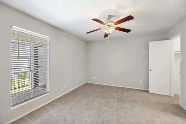 an empty room with windows and fan
