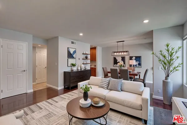 a living room with furniture kitchen view and a wooden floor