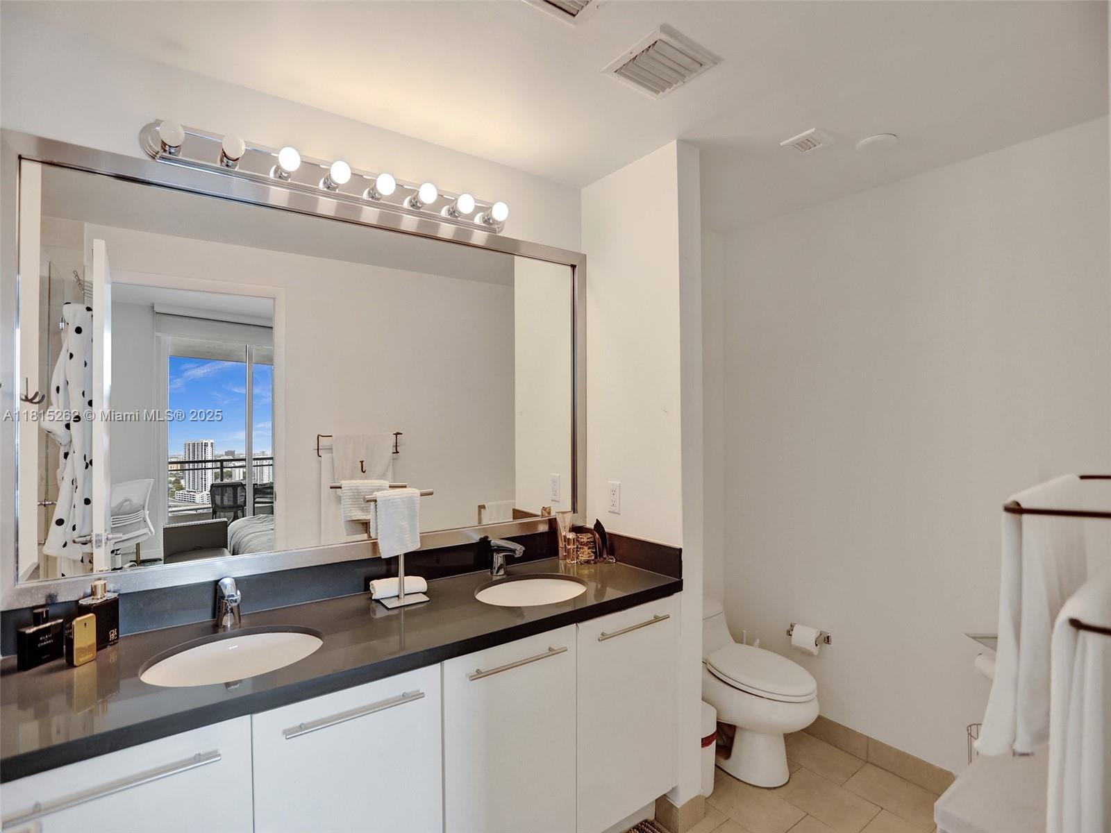 90 Southwest 3rd Street, Unit 2809 Miami, FL 33130 - Photo 20 of 67 a bathroom with a granite countertop sink and a mirror with toilet