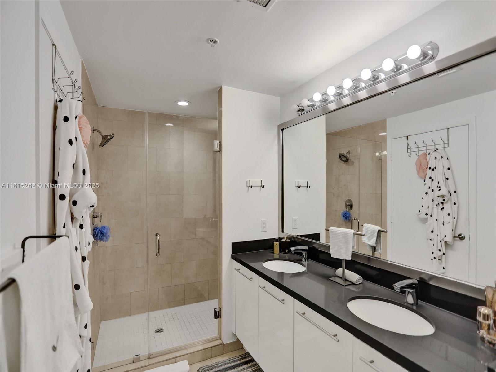 90 Southwest 3rd Street, Unit 2809 Miami, FL 33130 - Photo 21 of 67 a bathroom with a granite countertop double vanity sink a mirror a shower and a bathtub