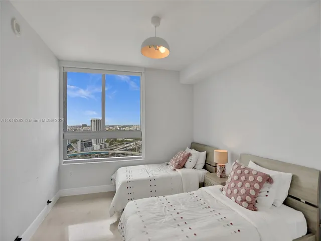 a bedroom with two beds and a large window