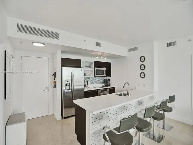 a room with stainless steel appliances kitchen island granite countertop a view of living room
