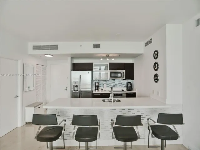 a kitchen with stainless steel appliances kitchen island granite countertop a sink a stove and refrigerator