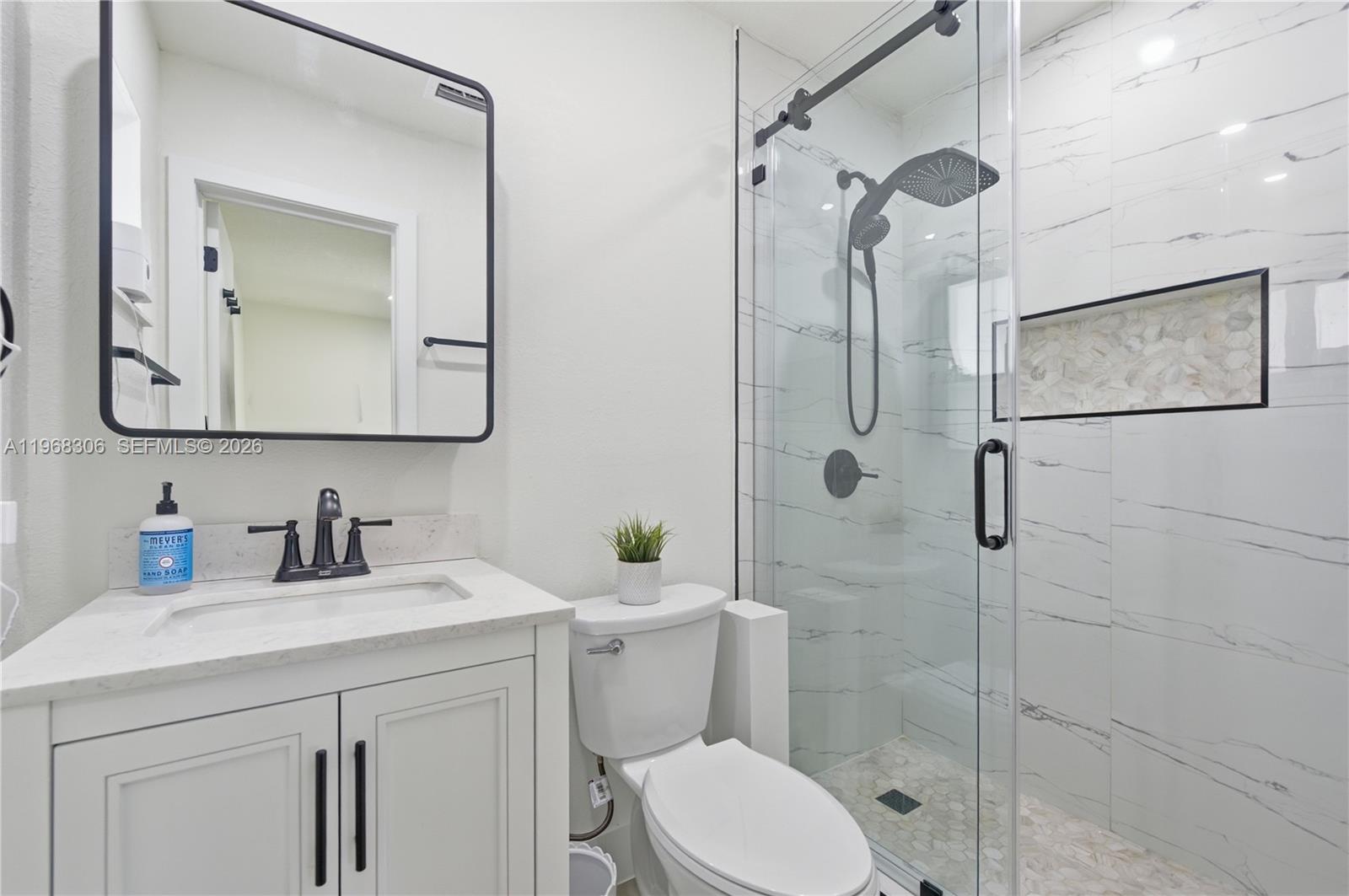 7491 Raleigh Street Hollywood, FL 33024 - Photo 7 of 28 a bathroom with a toilet sink vanity and mirror