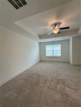 an empty room with chandelier fan and windows