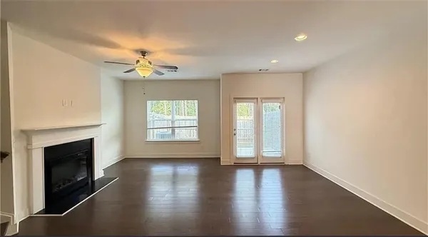 an empty room with wooden floor fireplace and windows
