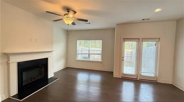 an empty room with wooden floor fireplace and windows