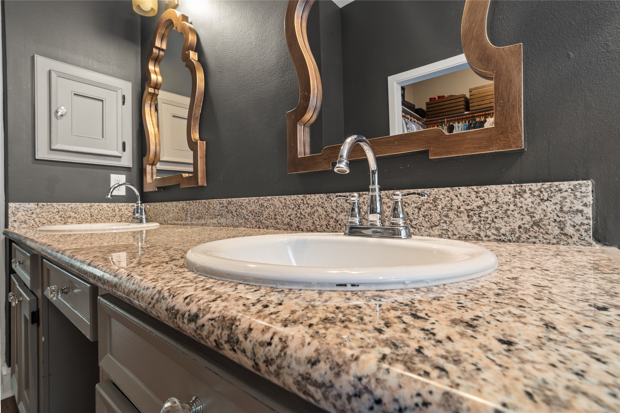 36 Wind River Drive Conroe, TX 77384 - Photo 34 of 45 This bathroom features a stylish double vanity with granite countertops, sleek chrome faucets, and unique decorative mirrors, set against elegant dark walls.