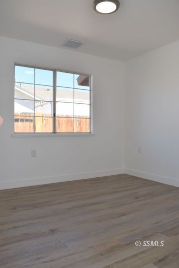 1132 West Robert Avenue Ridgecrest, CA 93555 - Photo 21 of 38 a view of an empty room with wooden floor and a window