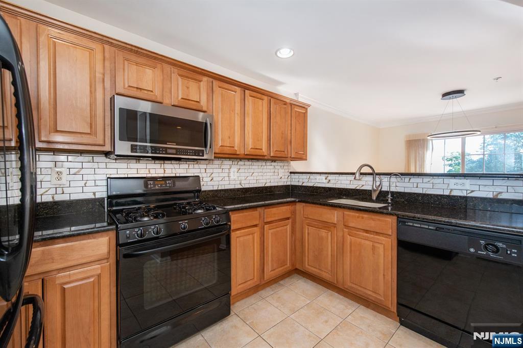 146 Summit Ridge, Unit 1406 Pompton Lakes, NJ 07442 - Photo 6 of 26 a kitchen with granite countertop wooden cabinets and a stove top oven