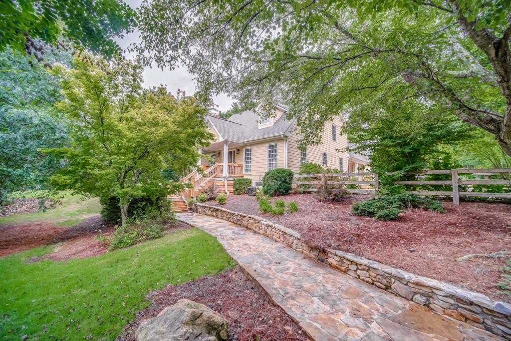 2465 Jep Wheeler Road Woodstock, GA 30188 - Photo 1 of 1 A Walkway of mellow flagstone leads from the driveway to the inviting entrance tucked behind perfectly placed trees.