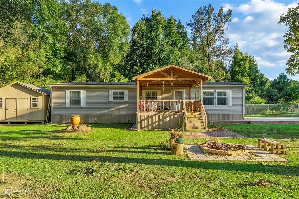 Manufactured / mobile home featuring a storage shed and view of scattered trees