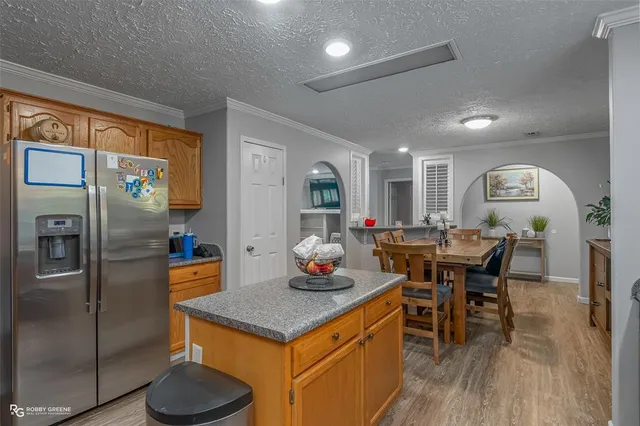 a kitchen with stainless steel appliances granite countertop a table chairs and a refrigerator
