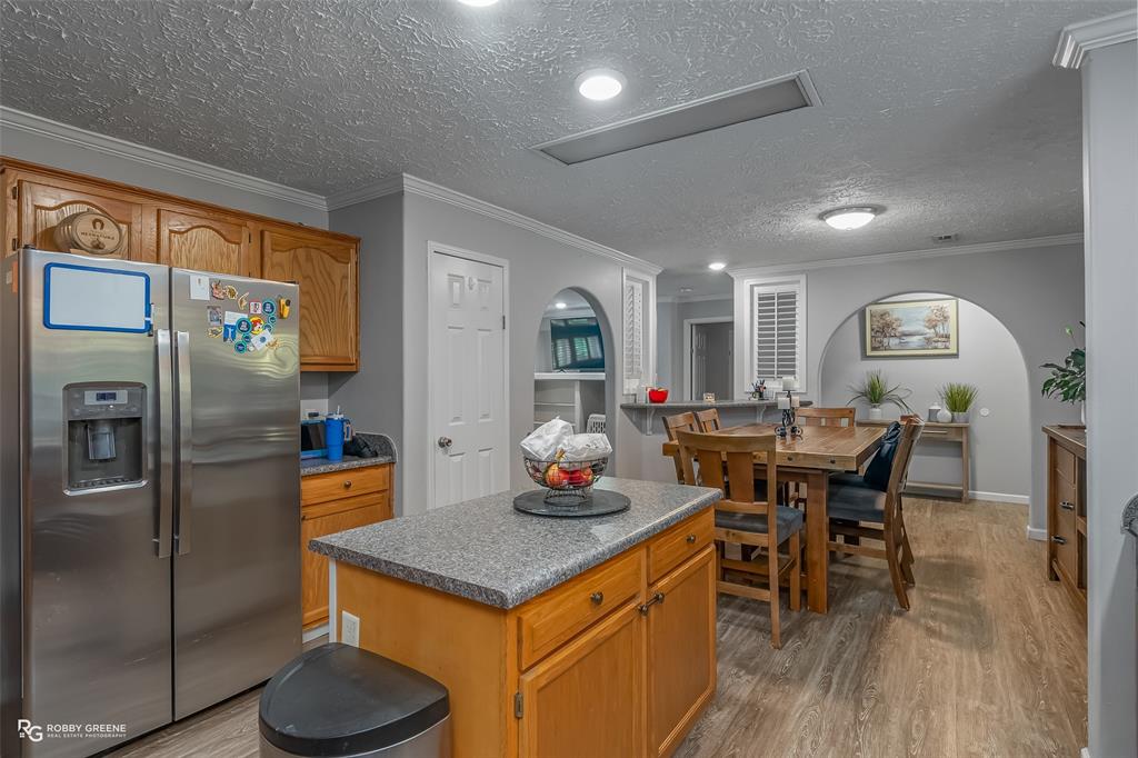 8287 Jefferson Paige Road Shreveport, LA 71119 - Photo 11 of 40 Kitchen with stainless steel fridge, light wood-type flooring, a textured ceiling, ornamental molding, and brown cabinets