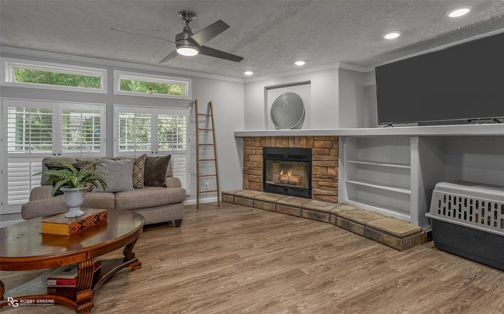 8287 Jefferson Paige Road Shreveport, LA 71119 - Photo 5 of 40 Living room with a textured ceiling, crown molding, wood finished floors, recessed lighting, and a stone fireplace
