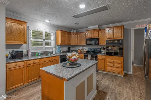 a kitchen with granite countertop wooden floors stainless steel appliances and a window