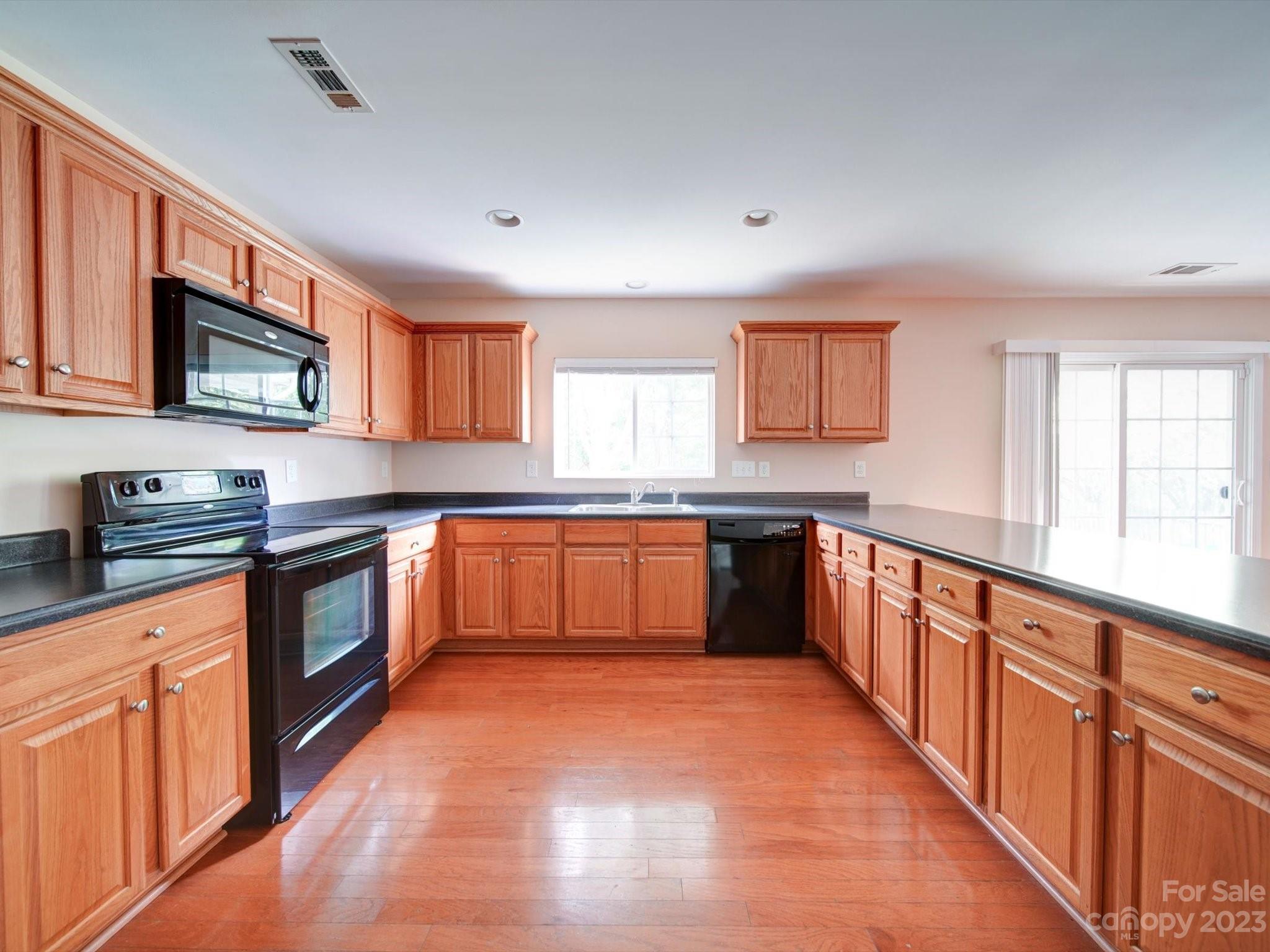 9221 Seamill Road Charlotte, NC 28278 - Photo 15 of 38 a kitchen with stainless steel appliances granite countertop wooden cabinets a stove top oven a sink and dishwasher with wooden floor