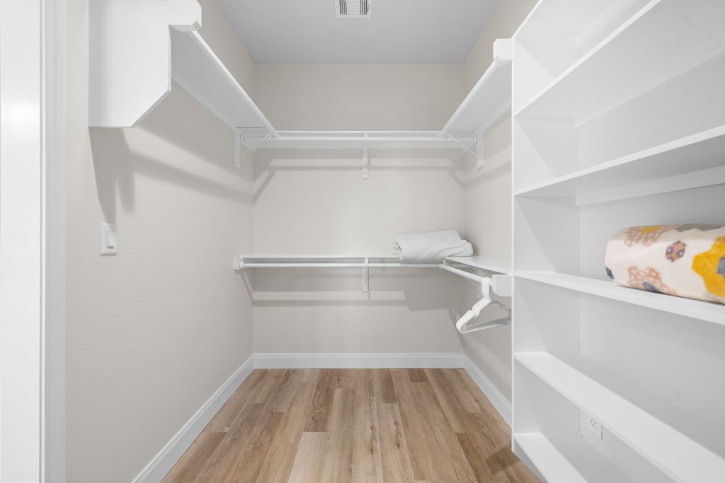 1703 County Road, Unit 217 Giddings, TX 78942 - Photo 10 of 19 A spacious walk-in closet features built-in shelving, hanging rods, and wood flooring.