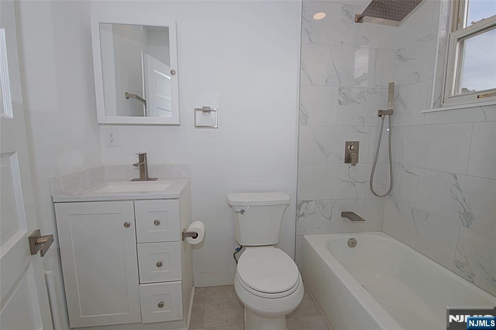 63 Van Winkle Avenue, Unit 2 Garfield, NJ 07026 - Photo 9 of 15 a bathroom with a sink a toilet and shower