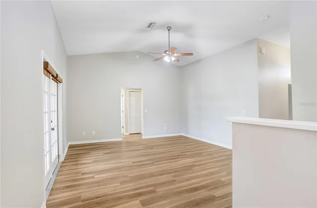 a view of an empty room with window and wooden floor