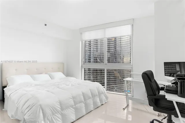 a bedroom with a bed a chair and a large window