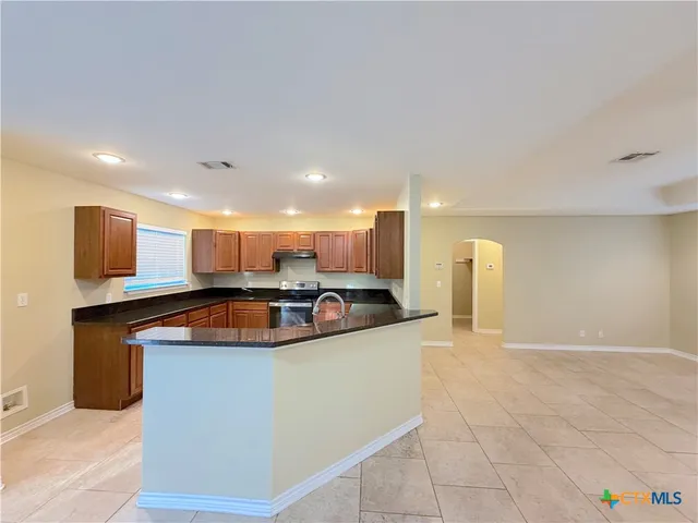 a kitchen with stainless steel appliances granite countertop a sink a stove and a refrigerator