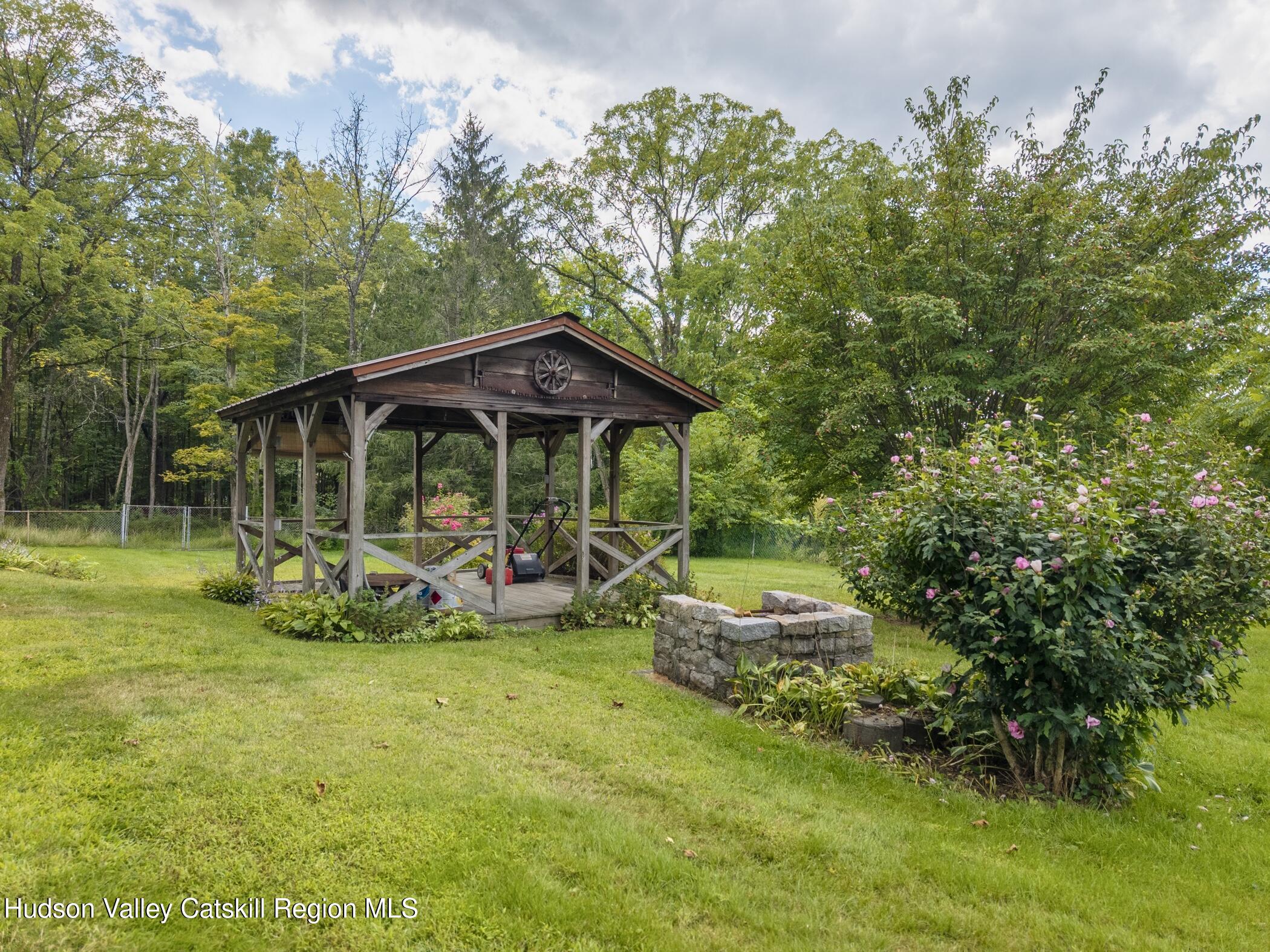 23 Maple Street Rifton, NY 12471 - Photo 36 of 43 a view of a patio with table and chairs under an umbrella with large trees