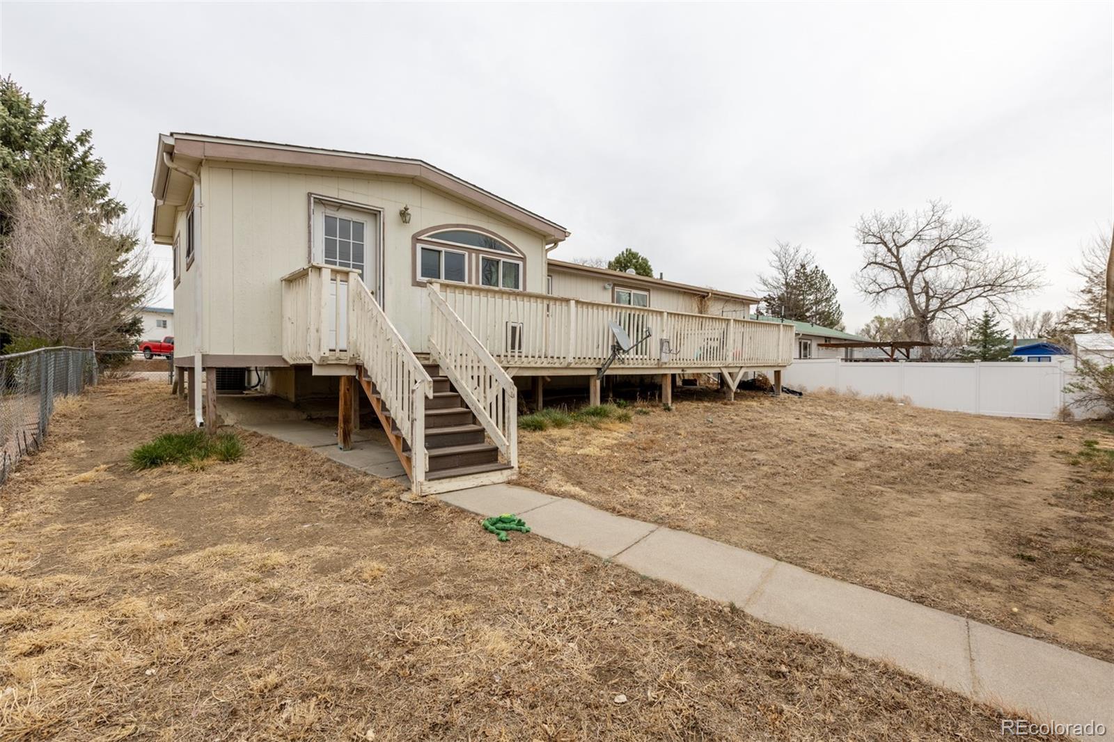 114 6th Street Hugo, CO 80821 - Photo 5 of 50 a white house that has a small yard and a wooden fence