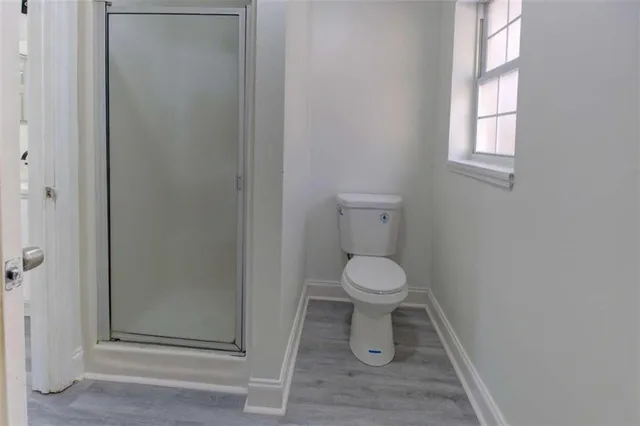 an empty room with wooden floor cabinet and windows