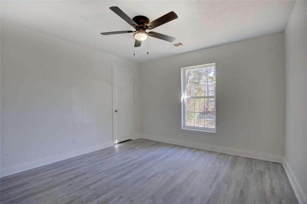 390 Rocky Point Road Covington, GA 30014 - Photo 17 of 19 an empty room with wooden floor ceiling fan and windows