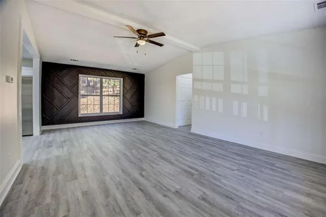a view of an empty room with a window and wooden floor