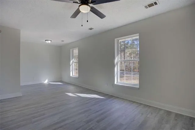 a view of an empty room with window and wooden floor
