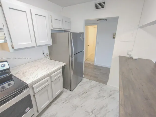a kitchen with a refrigerator sink and cabinets