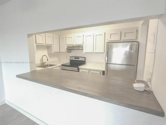 a kitchen with stainless steel appliances granite countertop a sink refrigerator and cabinets