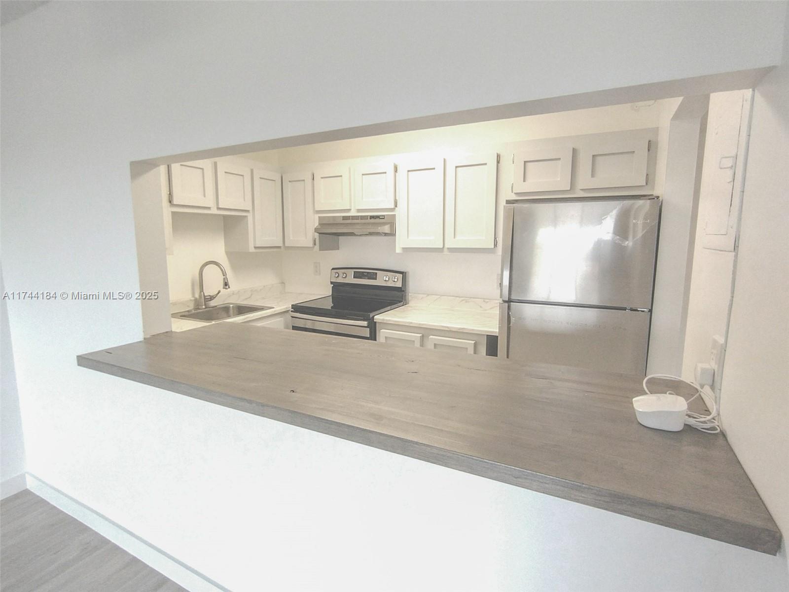 4174 Inverrary Drive, Unit 706 Lauderhill, FL 33319 - Photo 5 of 59 a kitchen with stainless steel appliances granite countertop a sink refrigerator and cabinets