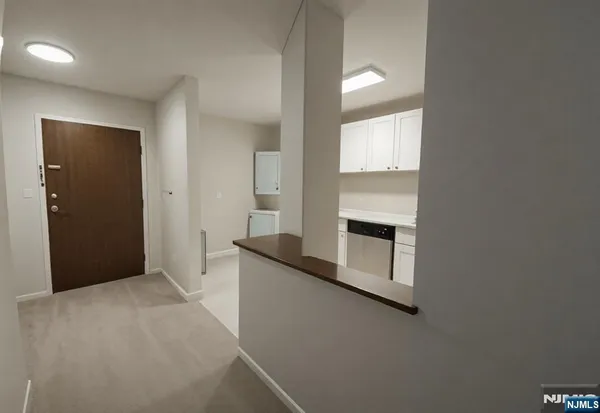 a view of a kitchen with an empty room and wooden floor