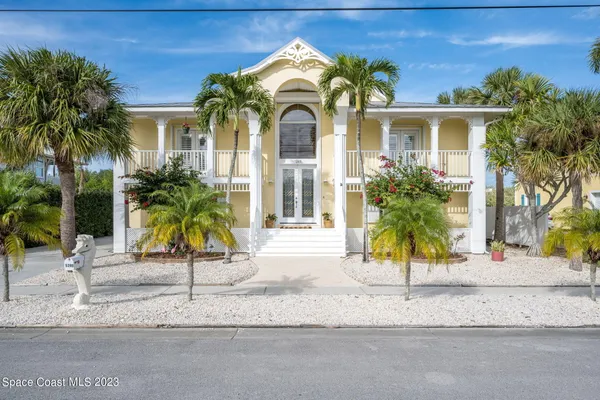 a view of a house with a small yard and palm trees