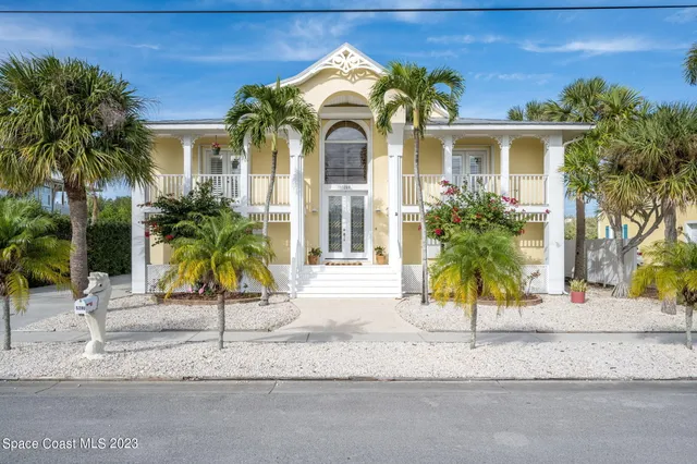 a view of a house with a small yard and palm trees