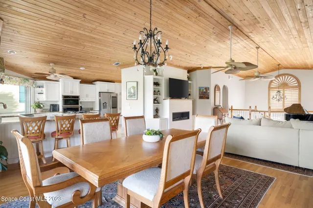 a dining room with wooden floor a chandelier a wooden table and chairs