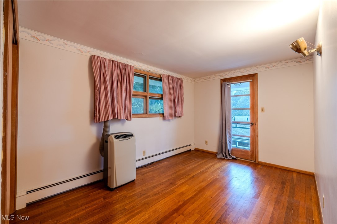 1950 Rush Road Wickliffe, OH 44092 - Photo 16 of 50 Unfurnished room featuring a baseboard radiator, wood-type flooring, and plenty of natural light