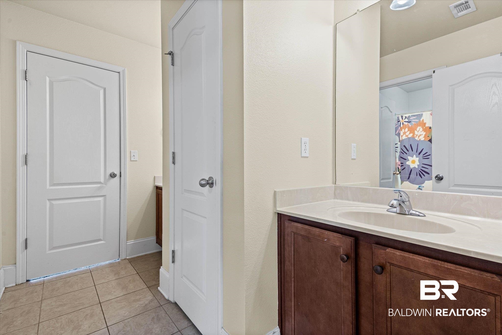 585 Sheffield Avenue Foley, AL 36535 - Photo 21 of 45 Bathroom vanity featuring wood-finish cabinetry, a light-toned countertop, and an integrated sink with a chrome faucet